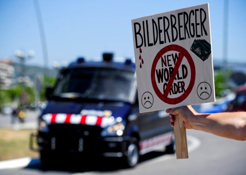 A placard against the Bilderberg Group meeting is held in front of a anti-riot van on June