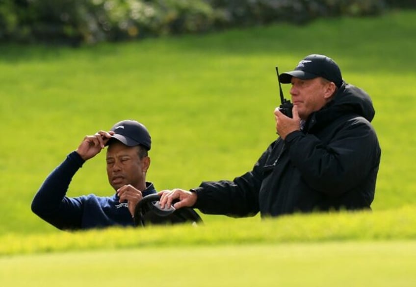 Golf superstar Tiger Woods speaks with a rules official after withdrawing from the Genesis