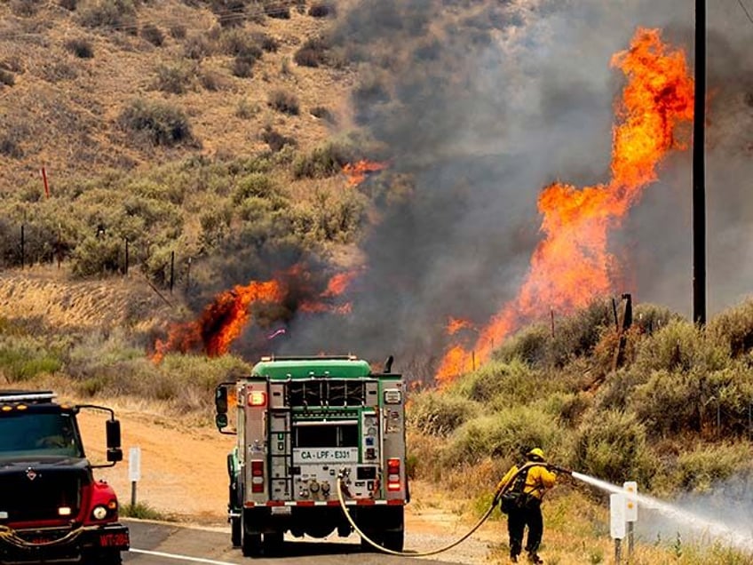 A firefighter battles the Madre Fire as it makes a run along Highway 166, Thursday, July 3