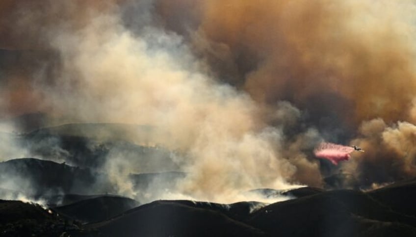 In this aerial view taken from a helicopter, an air tanker drops fire retardant on the Ken