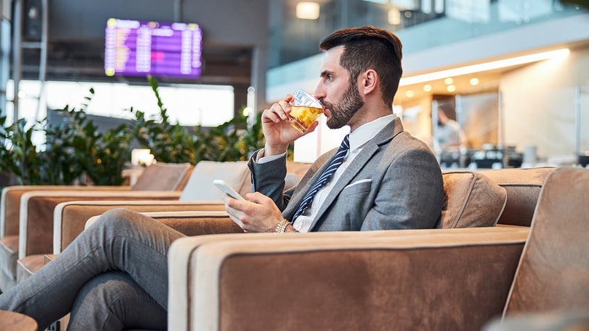 man sips on cocktail at airport