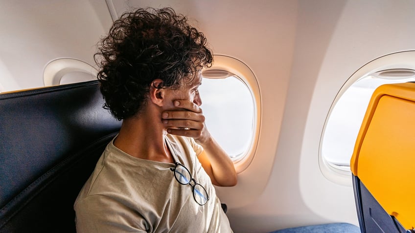 man covering mouth on flight