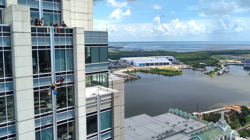 fire personnel rescuing window washer outside skyscraper