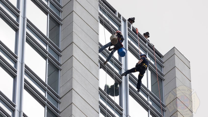 fire personnel rescuing window washer outside skyscraper