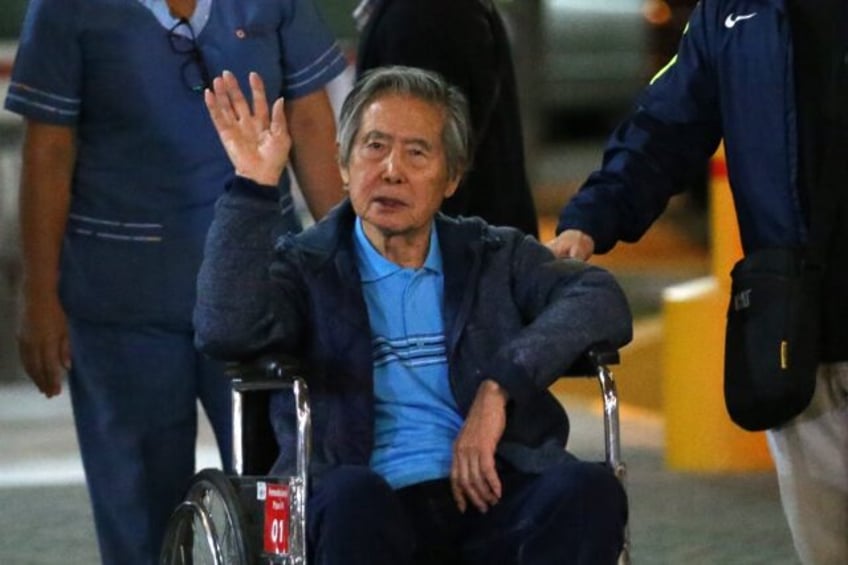 Peru's former President Alberto Fujimori waves to supporters as he is wheeled out of the C