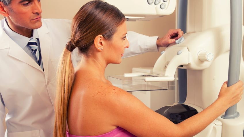 doctor checking mammography machine scan with patient woman in 40s.