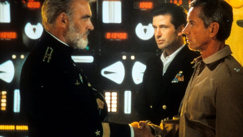 Sean Connery shakes the hand of Scott Glenn with Alec Baldwin watching from behind in a scene from "The Hunt For Red October"