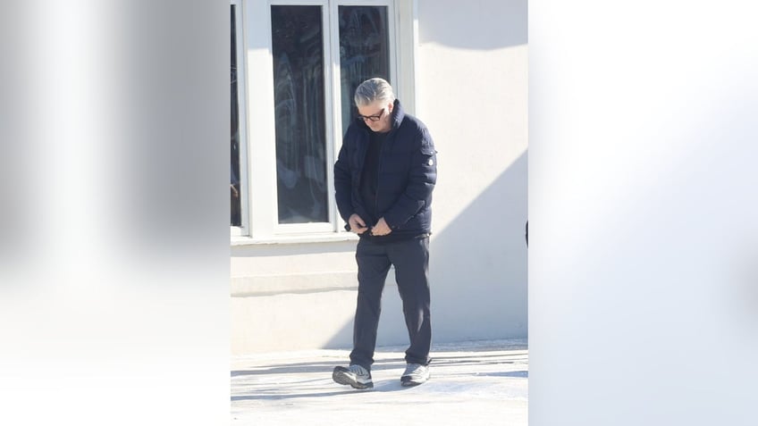 Alec Baldwin zips up his jacket outside restaurant in The Hamptons