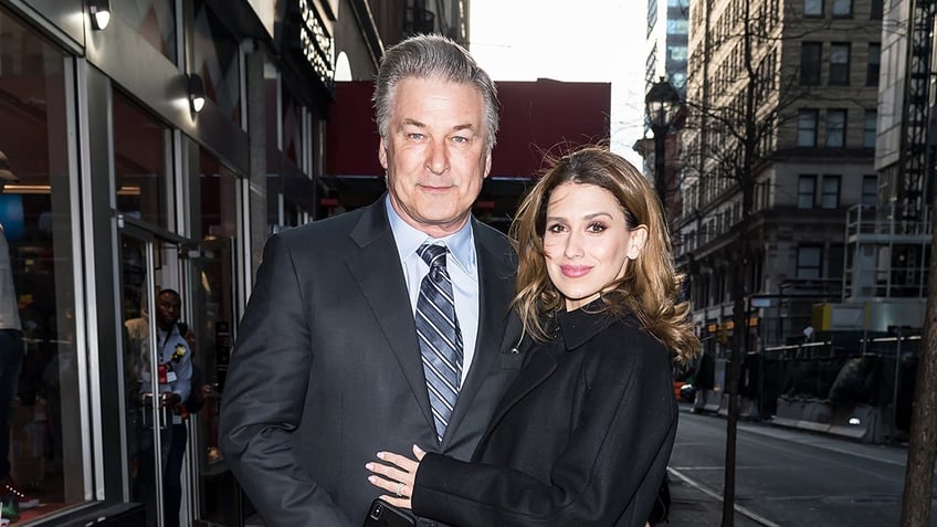 Alec Baldwin wears a suit and tie with wife Hilaria Baldwin bundled up in a long coat.