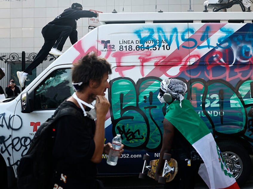 LOS ANGELES, CALIFORNIA - JUNE 09: (EDITORS NOTE: Image contains profanity) A person climb