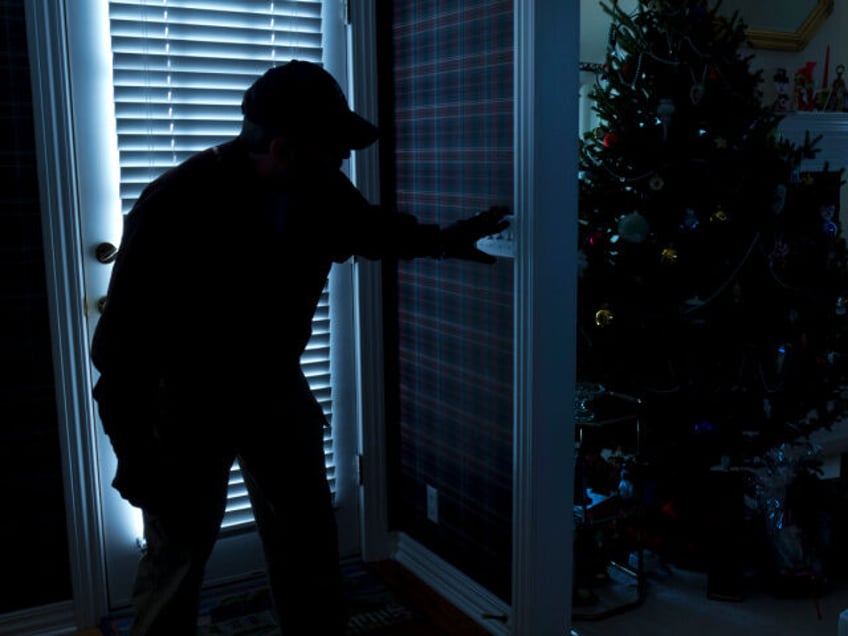 This photo illustrates a burglary or thief breaking into a home at night through a back door during the Christmas Holiday Season. View from inside the residence.