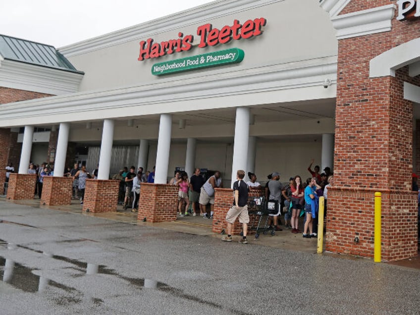 People wait in line to buy food and supplies at one of the few places open in Wilmington,