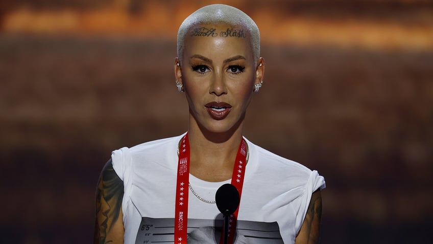 Amber Rose in a white T-shirt with Donald Trump's mugshot on it stands behind a podium at the RNC