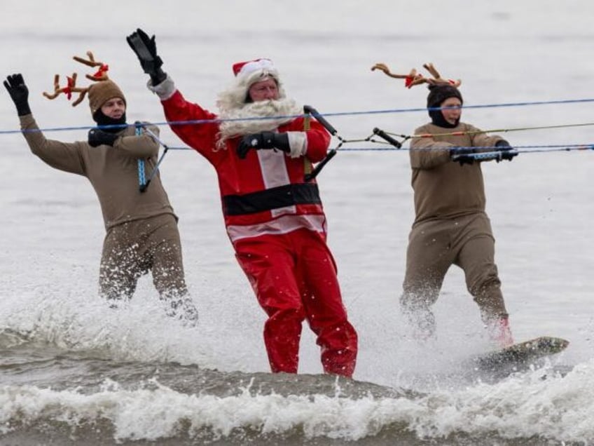 Men dressed as Santa Claus and his reindeer perform during the Water Skiing Santa Show in Alexandria, Virginia, on December 24, 2023. The show, including a waterskiing Santa, reindeer, elves, the Grinch and Frosty the Snowman, has been performing on the Potomac River on Christmas Eve for 38 years. (Photo …