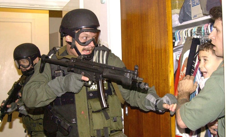 Officer holds gun pointed at man and boy