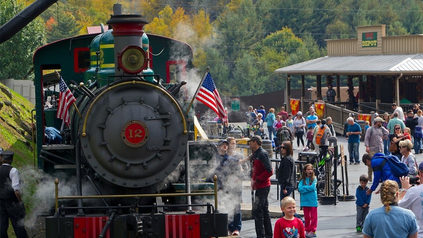 Train travels past people at Tweetsie Railroad park