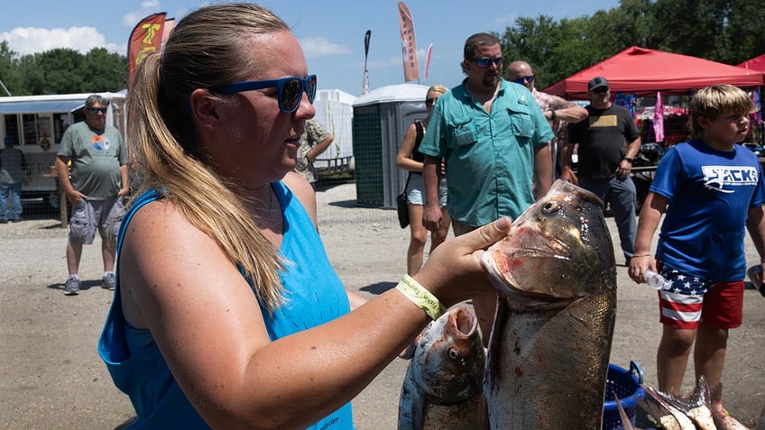 A woman holds two dead invasive carp during a tournament in Illinois.