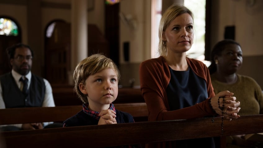 child and woman hands clasped in church