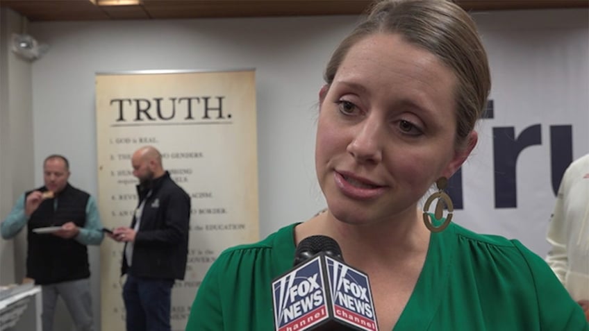 Female voter in green shirt talking with Fox News Channel Microphone in front of her