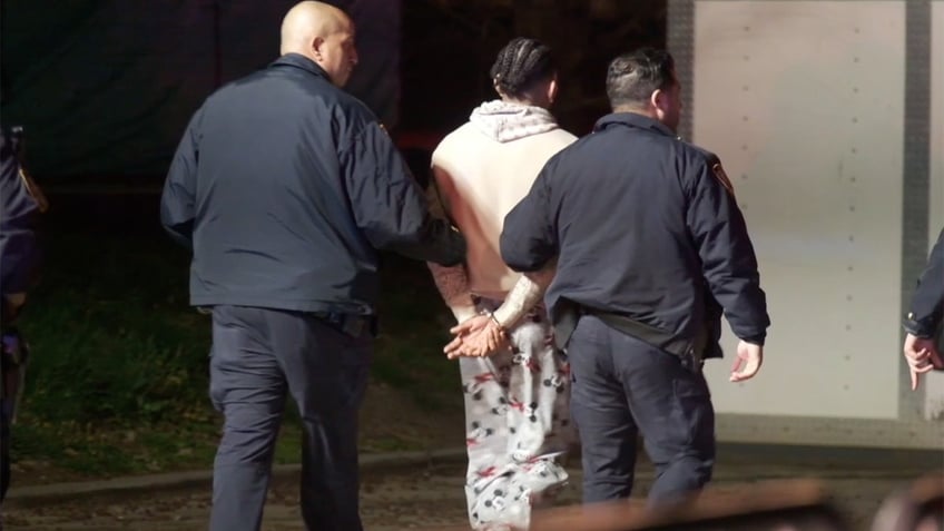 A man is taken away from a migrant shelter in handcuffs on Randall's Island