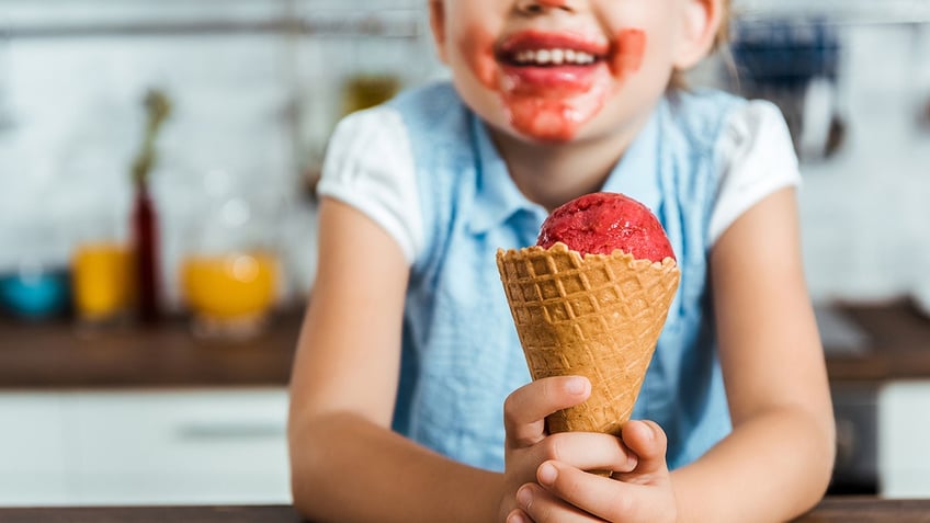 cropped shot of adorable happy child holding delicious ice cream cone