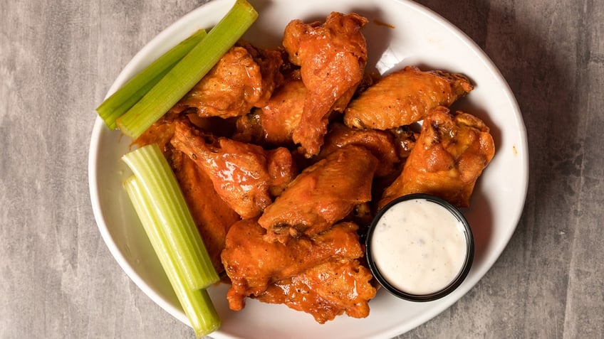 Buffalo wings with celery and ranch dressing on a plate.