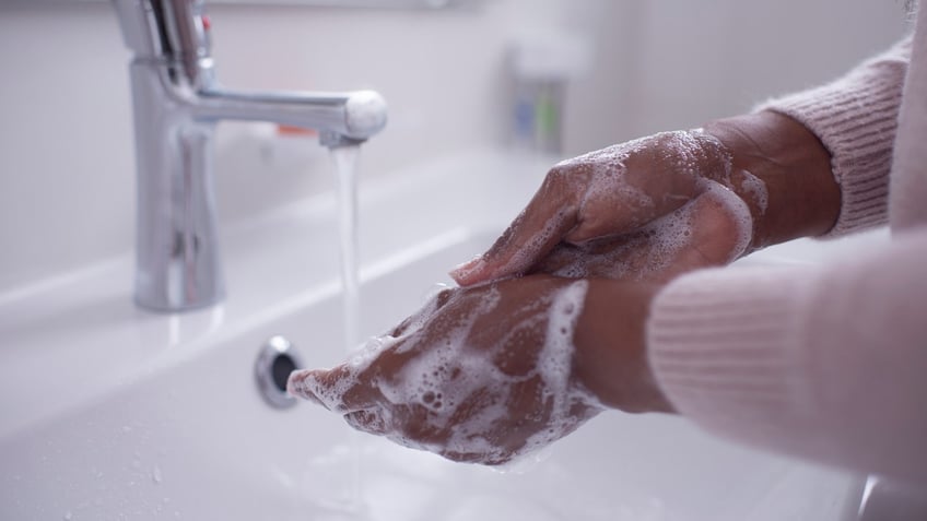 person washing their hands with soap and water