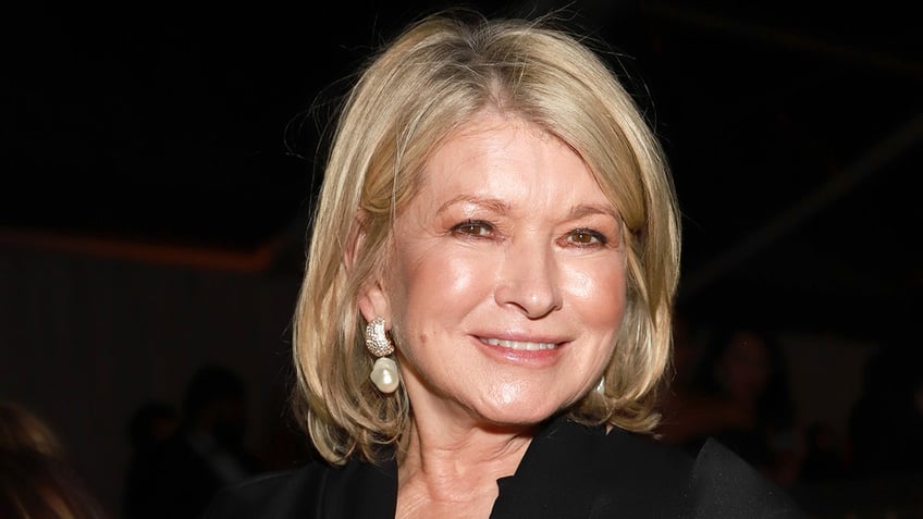 Martha Stewart smiles with pearl drop earrings in a black shirt