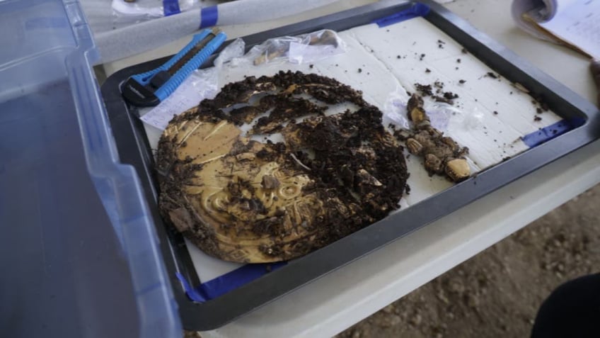 Gold disc on table covered in dirt