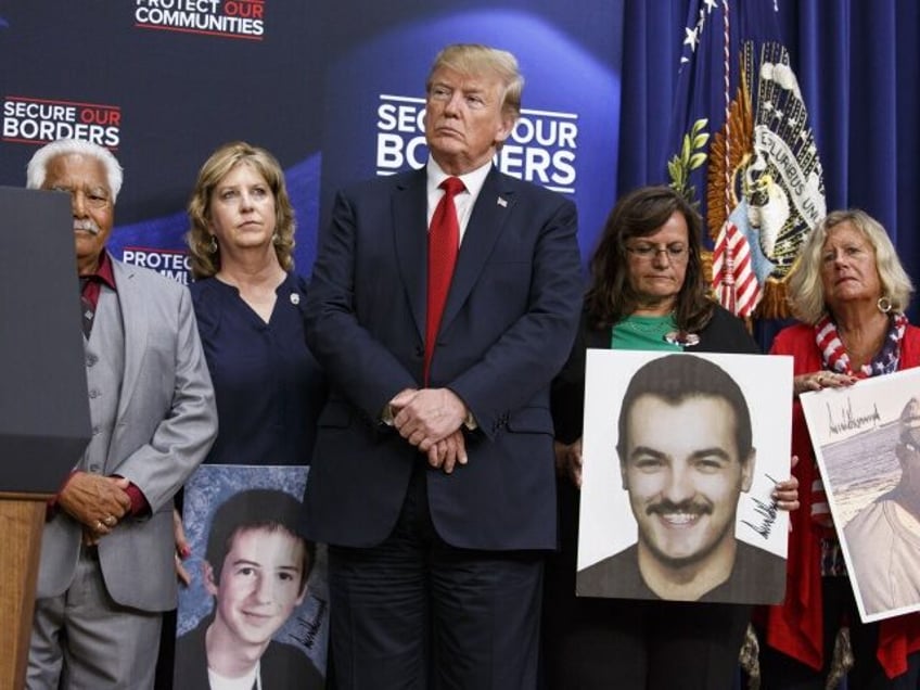 U.S. President Donald Trump stands with families who have lost relatives to crimes caused