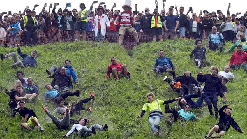 Participants tumble down a steep incline as onlookers cheer in the annual cheese rolling at Cooper's Hill in Brockworth, England, on May 27, 2024.