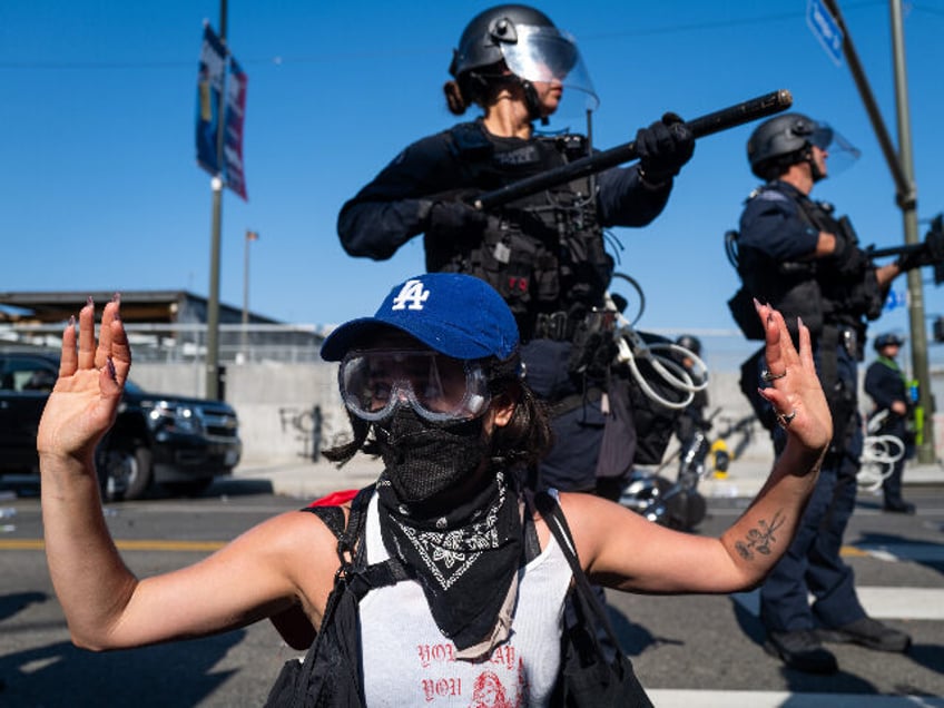 LOS ANGELES, CALIFORNIA - JUNE 08: A protester raises their hands in front of LAPD officer
