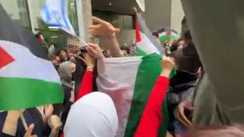 NYC protester covers a man with Palestinian flag