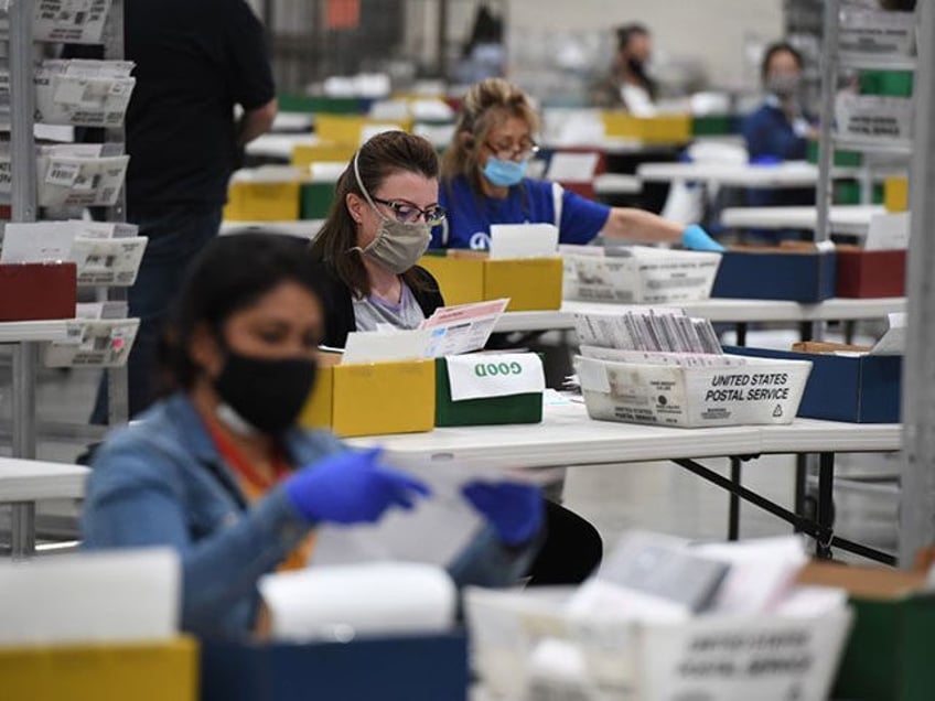 Election workers extract mail-in ballots from their envelopes and examine the ballot for i