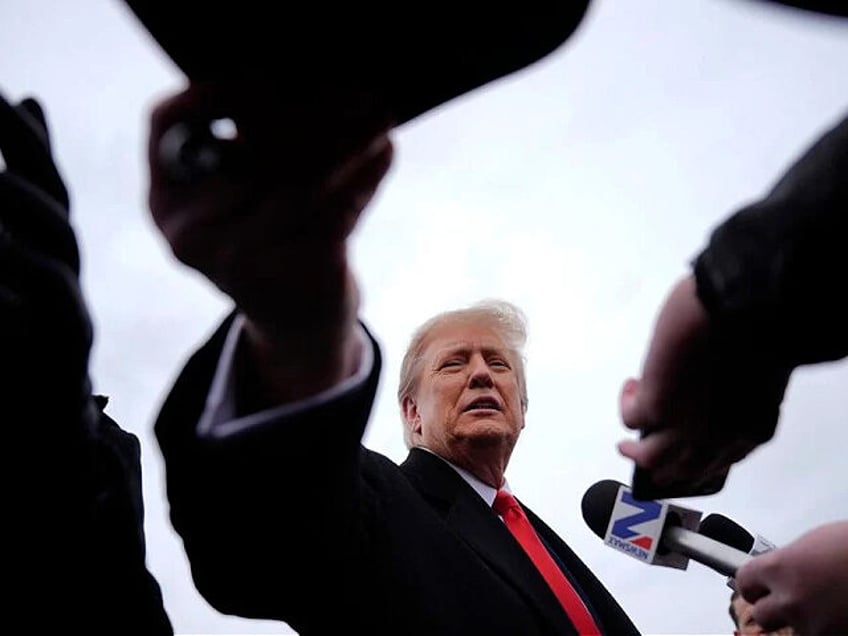 Republican presidential candidate former President Donald Trump hands an autographed hat to a supporter as he speaks with members of the media during a campaign stop in Londonderry, N.H., Tuesday, Jan. 23, 2024. (AP Photo/Matt Rourke)