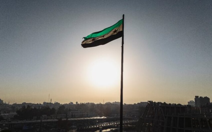 The Syrian independence-era flag, adopted by the country's new rulers, waves in the wind o