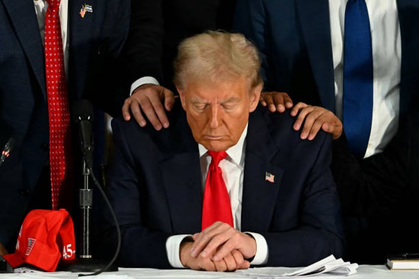 Former US President and Republican presidential candidate Donald Trump prays during a roundtable discussion with Latino community leaders at Trump...