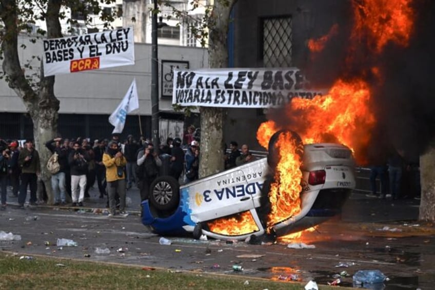 A car set aflame outside the Argentina's National Congress in Buenos Aires amid violent pr