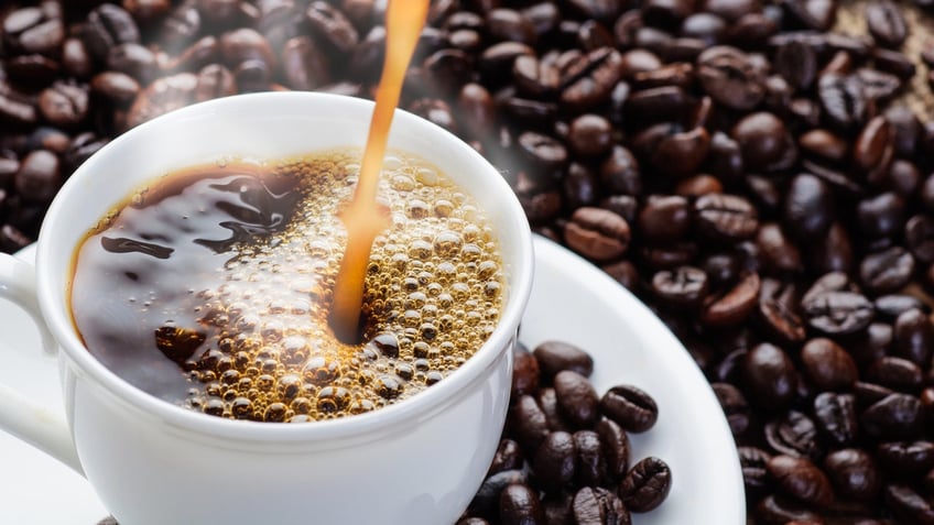 coffee pouring to cup surrounded by coffee beans