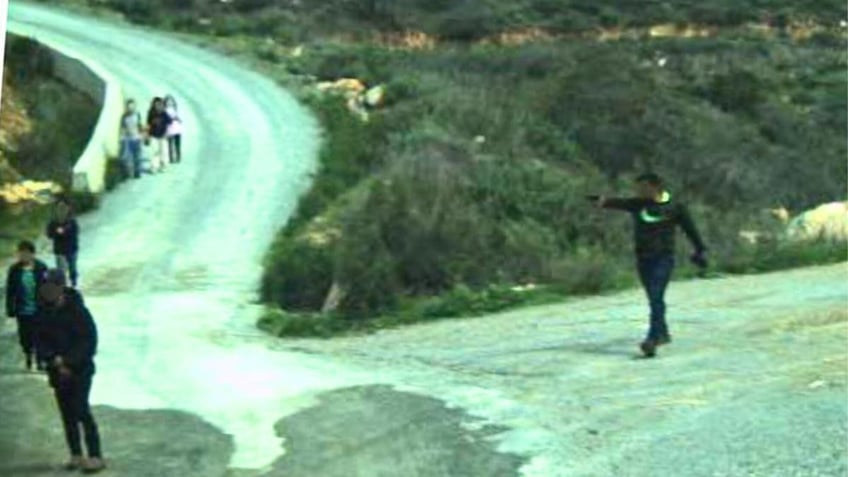 A man points a gun at a group of migrants