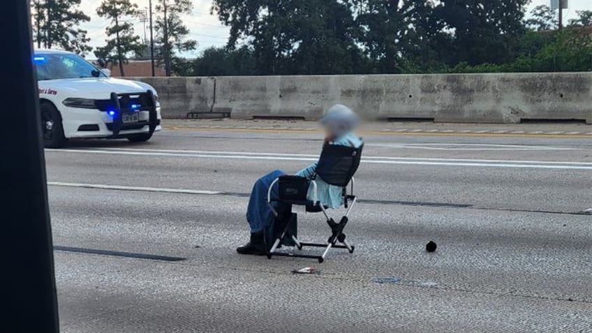 Armed woman sat in a chair on a busy highway