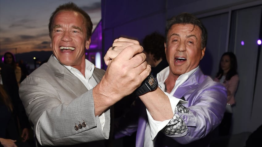 Arnold Schwarzenegger and Sylvester Stallone hold hands and dance in Cannes