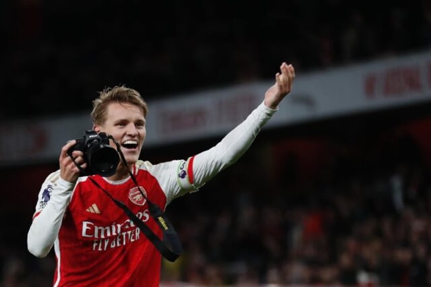 Martin Odegaard picks up a camera and takes pictures after Arsenal's win over Liverpool