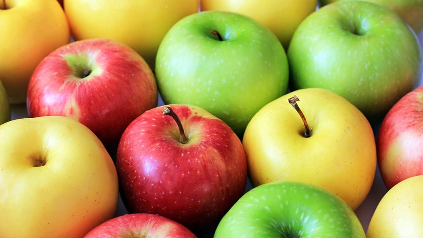 Red, yellow and green apples on a dark background.