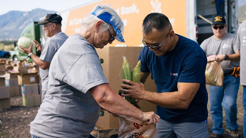 Volunteers packing corn into a bag at a volunteer event.