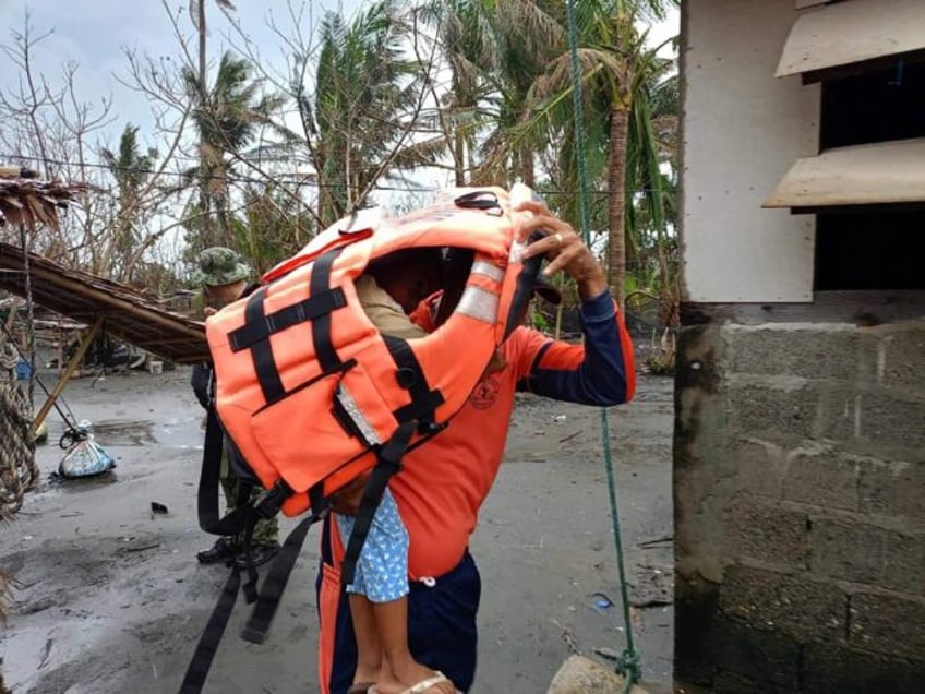 A rescuer carries a young resident during a forced evacuation operation in the northern Ph