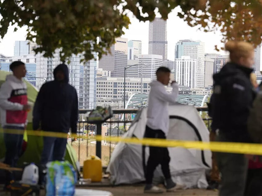 Occupants wait to see how police officers work during a city-sponsored sweep of an encampm