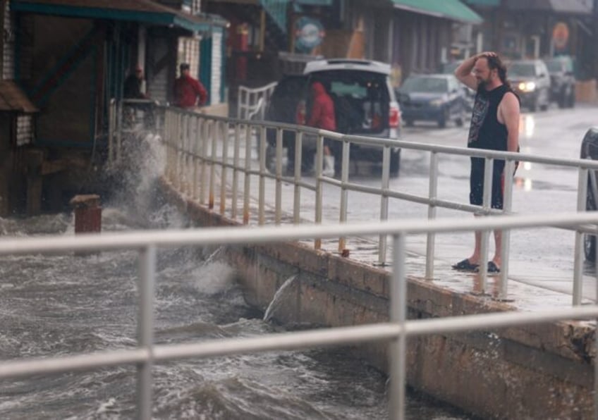 A rain-soaked man in Cedar Key, Florida observes waves kicked up by the winds of Tropical