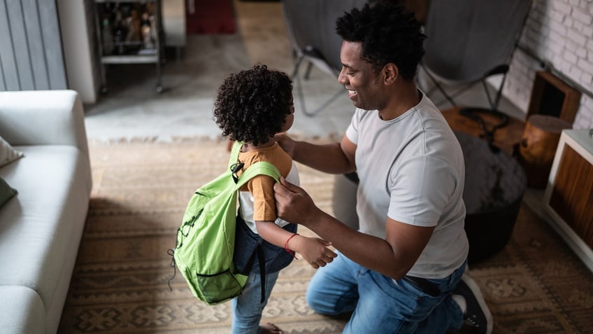 Father helping child with backpack