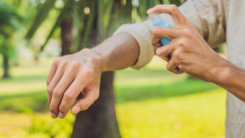 spraying mosquito repellant